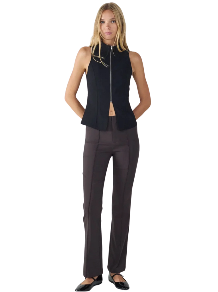 Mujer modelando de frente un conjunto completo de pantalón y top negro sonriendo a la cámara.